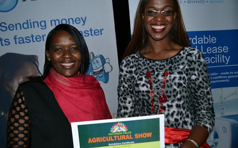 Nancy Sakala (FBC Bank Victoria Falls Branch Manager-right) and Emma Kaguru (Operations Officer) poses with the Victorial Falls Agricultural Show Exhibitor Award. 